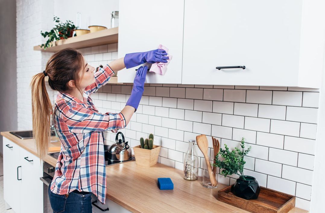 Woman cleaning kitchen cabinets 